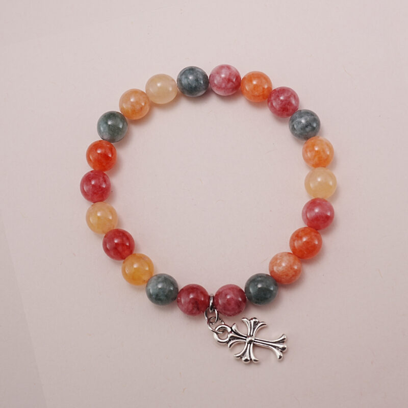 Colorful chalcedony bracelet with a silver heart charm displayed on a soft pink background.