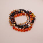 Flatlay of protective bracelet stack in red, orange, black and earthy colors.
