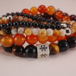 Close-up detail of protective bracelet stack featuring layered warm-toned beads.