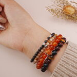 Protective multi-layer bracelet stack in warm tones displayed on wrist.