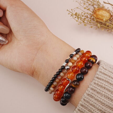 Protective multi-layer bracelet stack in warm tones displayed on wrist.