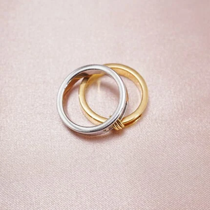 Two-tone stainless steel stacking rings in silver and gold displayed on soft fabric