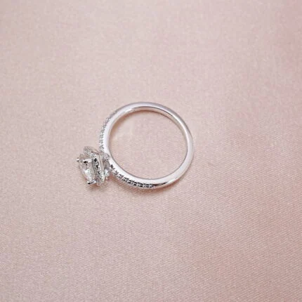 Heart-shaped moissanite halo ring in S925 silver displayed on a soft pink background