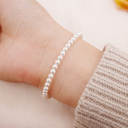 Delicate white pearl bracelet worn on wrist, showing minimal and elegant style.