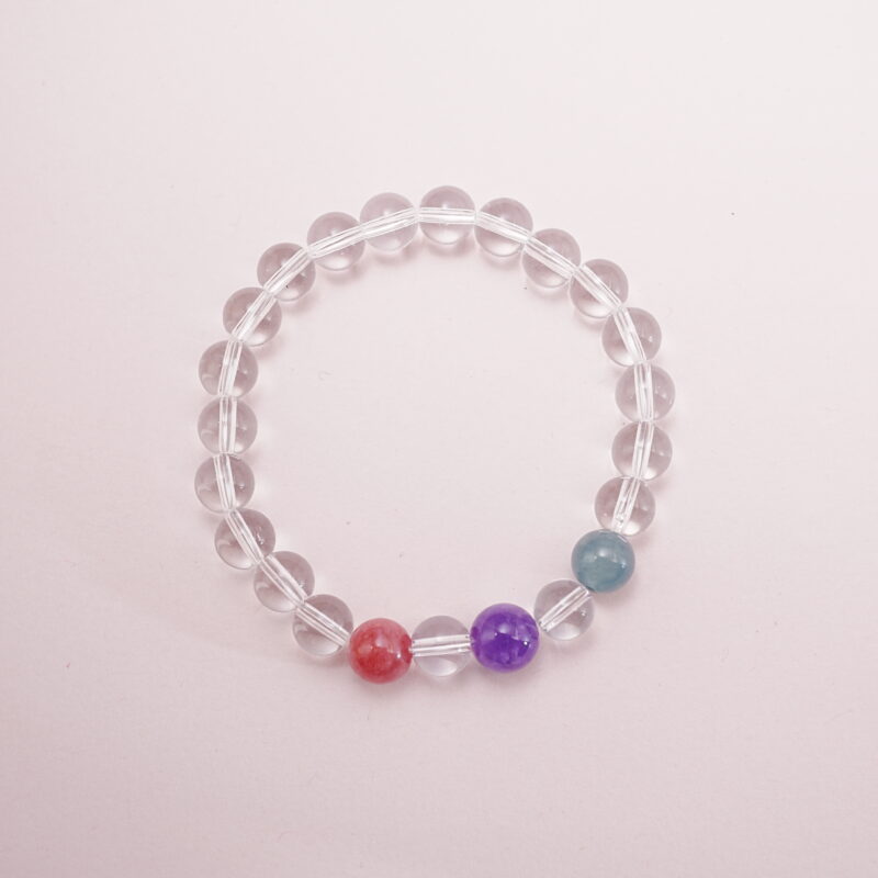 Clear quartz bracelet with three accent gemstones in red, purple, and teal