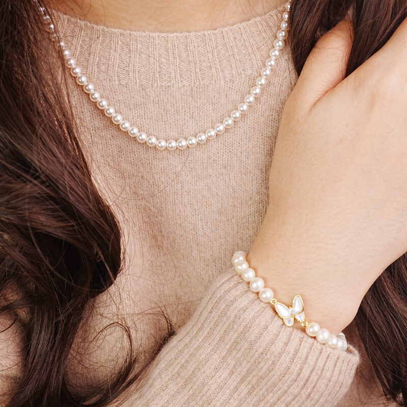 Woman wearing a classic single-strand pearl necklace with matching bracelet