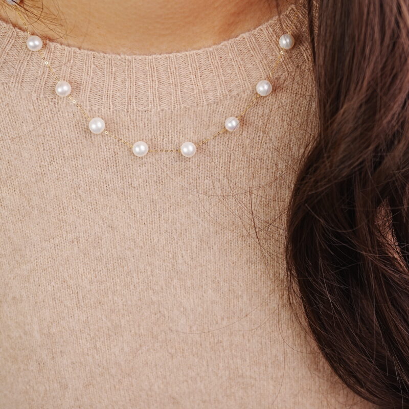 Woman wearing delicate pearl bracelet with gold chain accents