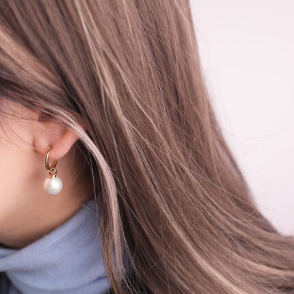 Woman wearing elegant pearl drop hoop earrings