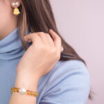 Model wearing a yellow quartz bead bracelet and yellow bell Christmas tree bow earrings, showcasing a festive holiday style.