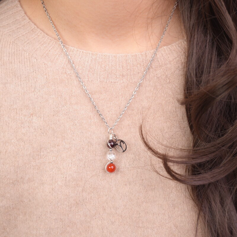 Model wearing Aries zodiac necklace with amethyst, clear quartz, and red agate.