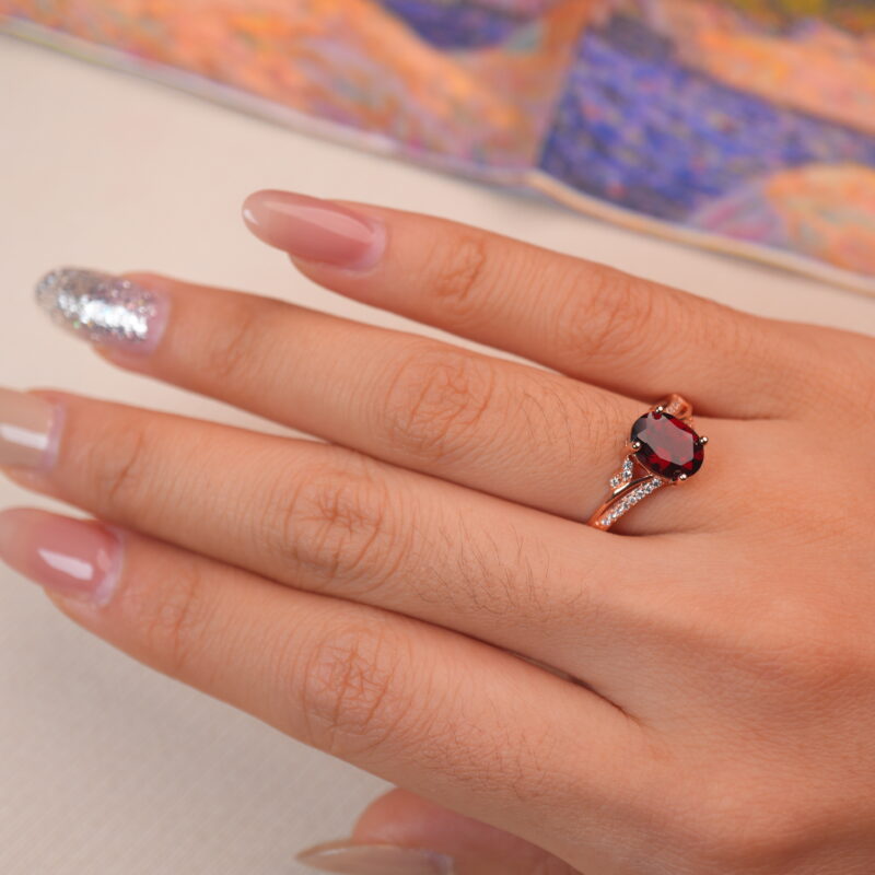 Rose gold oval ruby ring worn on a woman's hand, elegant gemstone jewelry