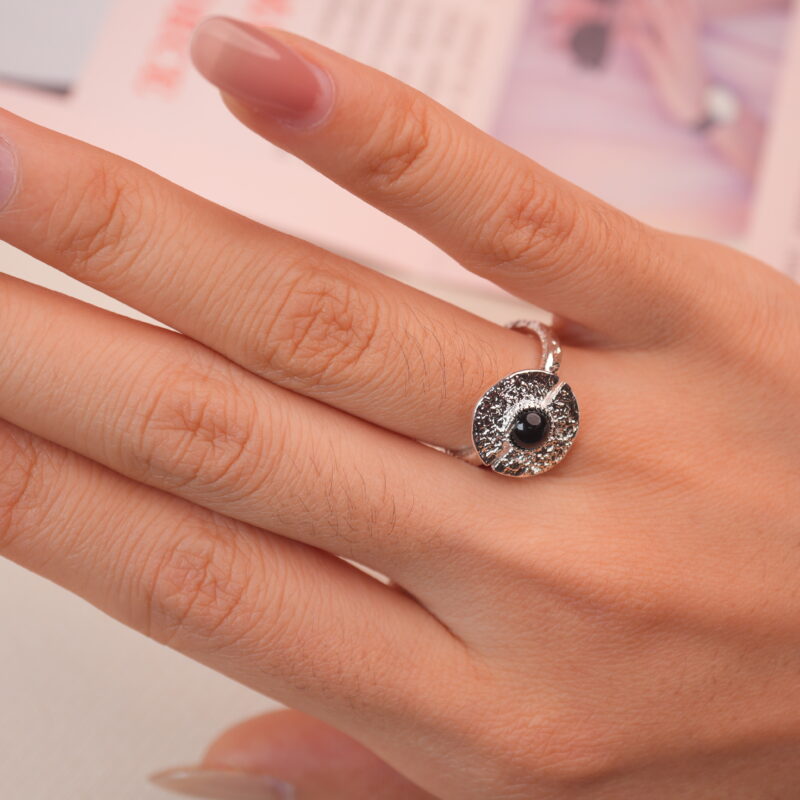 Silver evil eye ring with obsidian gemstone worn on hand, symbolizing spiritual grounding and protection.