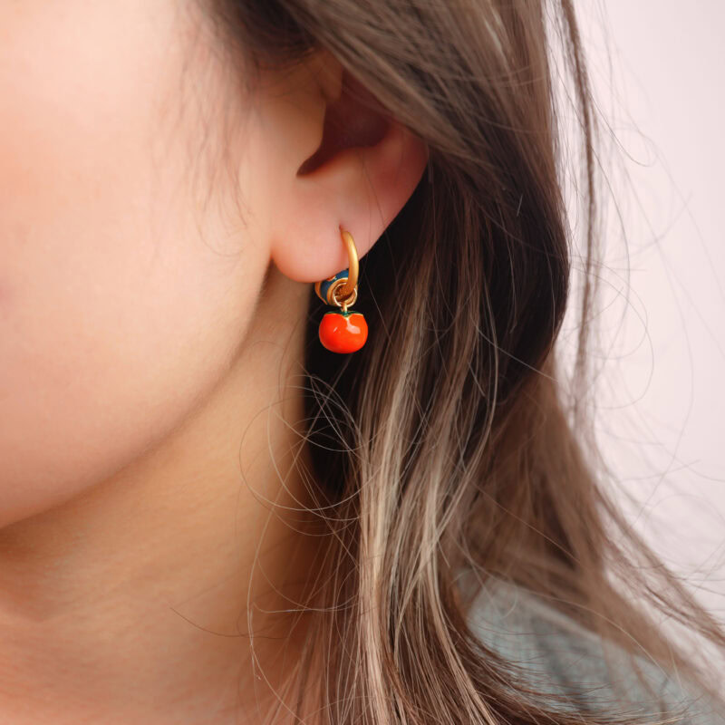 Model wearing colorful hoop earring with bright red bead charm