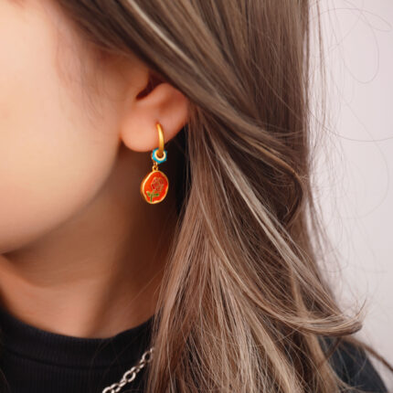 Close-up view of the red horse enamel earrings, highlighting the smooth enamel finish and playful design.