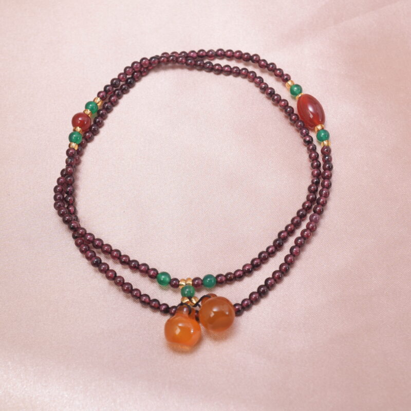 Garnet necklace with green accents and two orange crystal charms — main product image.