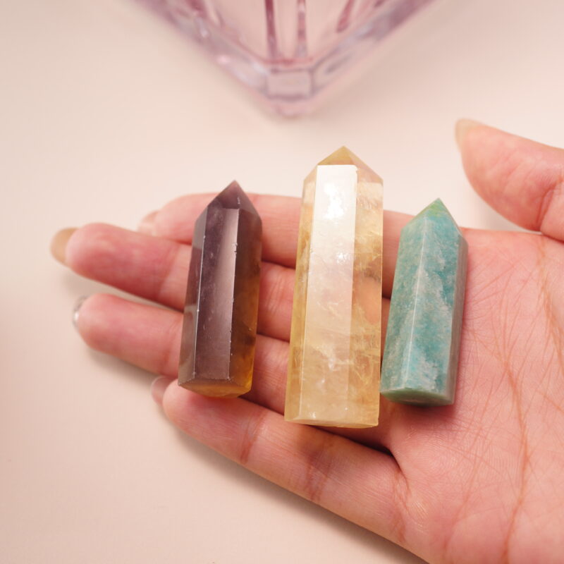 Three crystal points held in hand – smoky quartz, citrine, and amazonite – radiating bright, uplifting energy.