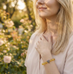 A woman wearing a crystal bracelet outdoors while gently touching her chest, expressing a calm and thoughtful lifestyle.