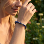 A woman wearing a crystal bracelet outdoors with a gentle hand movement, reflecting a natural and elegant lifestyle.