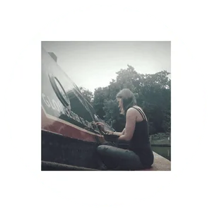 Woman playing piano on narrowboat with trees in background.