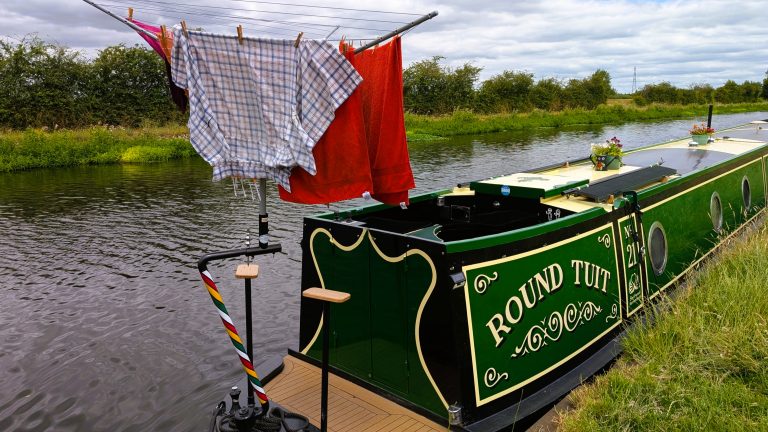 Narrowboat with laundry hanging to dry on the canal bank.