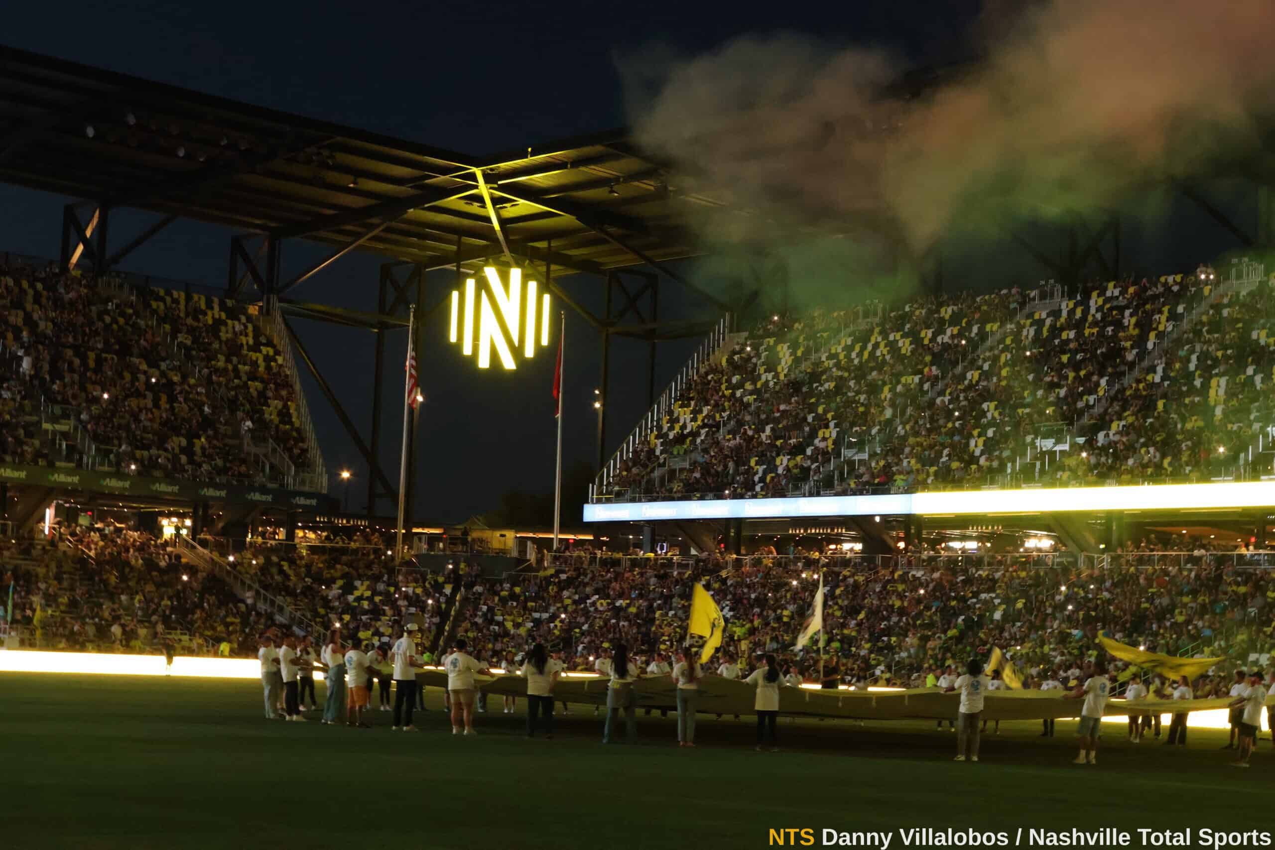 Vista panorámica de GEODIS Park con humo verde y el logo de Nashville SC iluminado antes del partido vs DC United