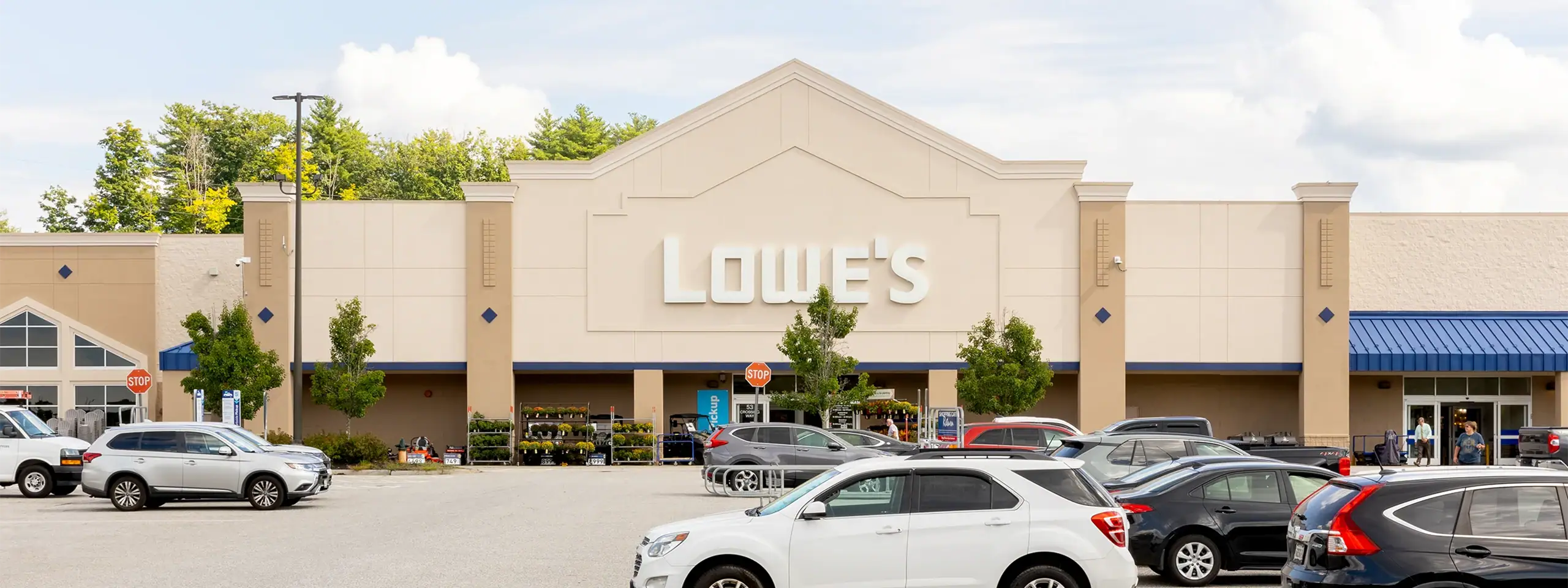 Lowe's store with parking lot and cars in front, clear sky background.