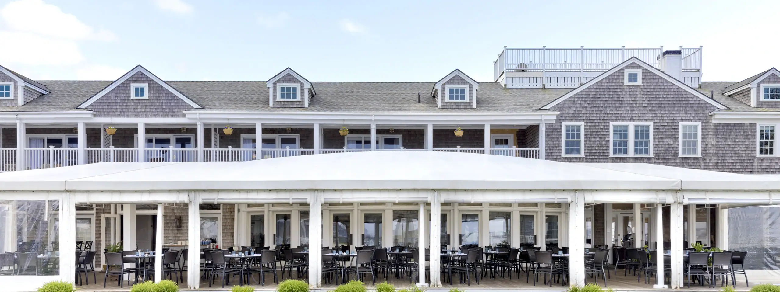 Exterior view of a seaside restaurant with outdoor seating and a large deck.