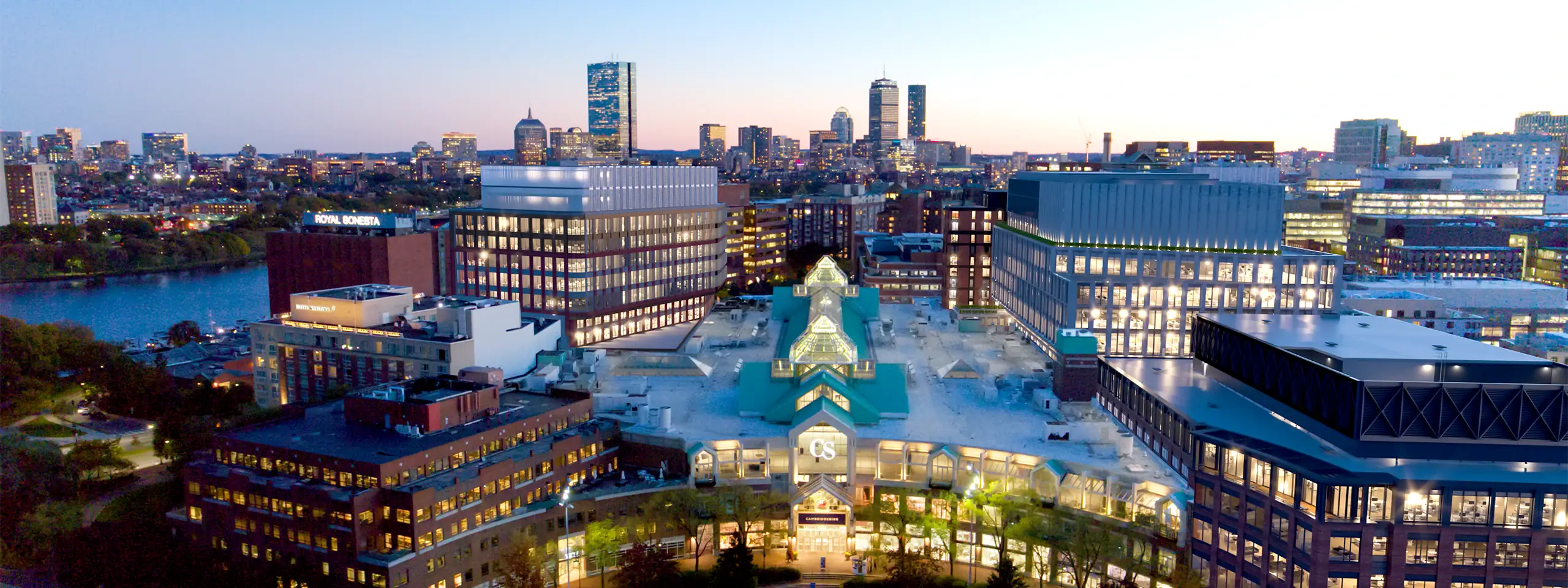 Night view of Boston with illuminated buildings and the Charles River.
