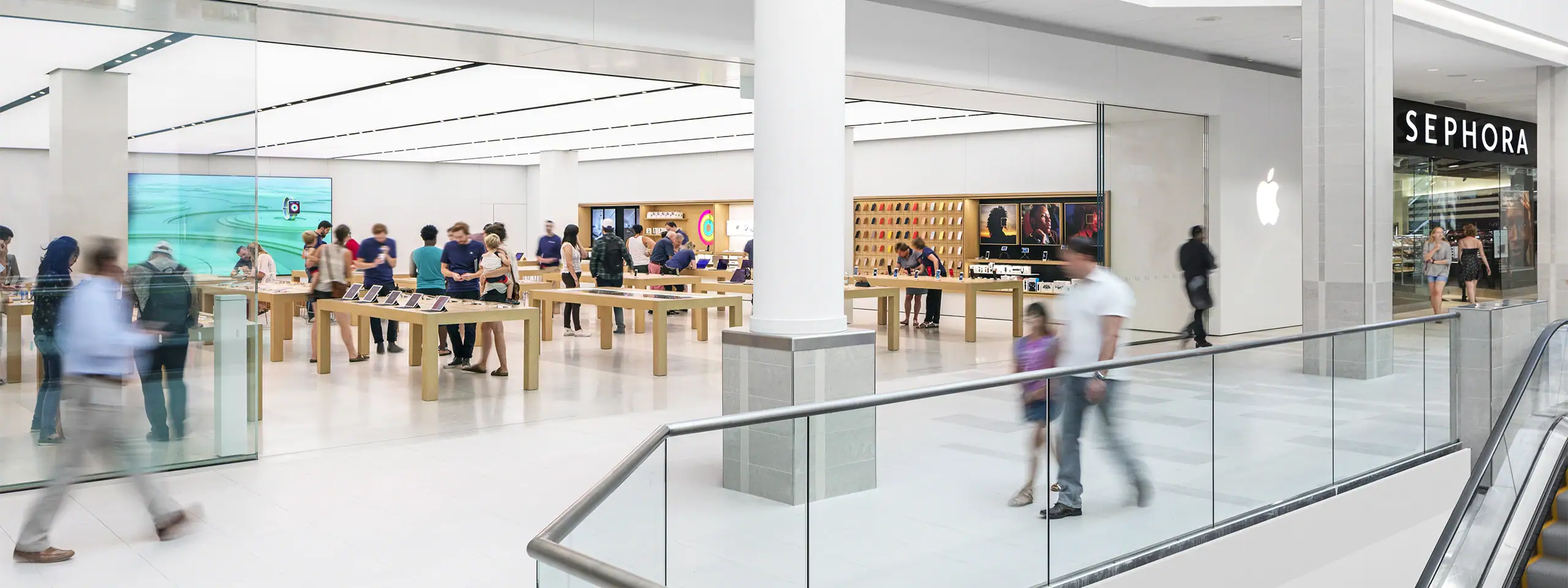 Shoppers inside a modern retail store with seating and a Sephora storefront.