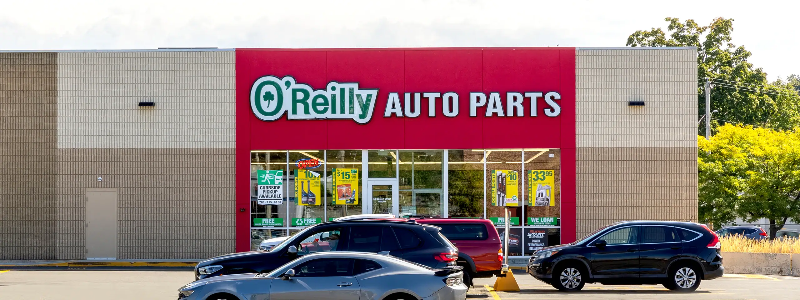 O'Reilly Auto Parts store exterior with signage and parked cars.