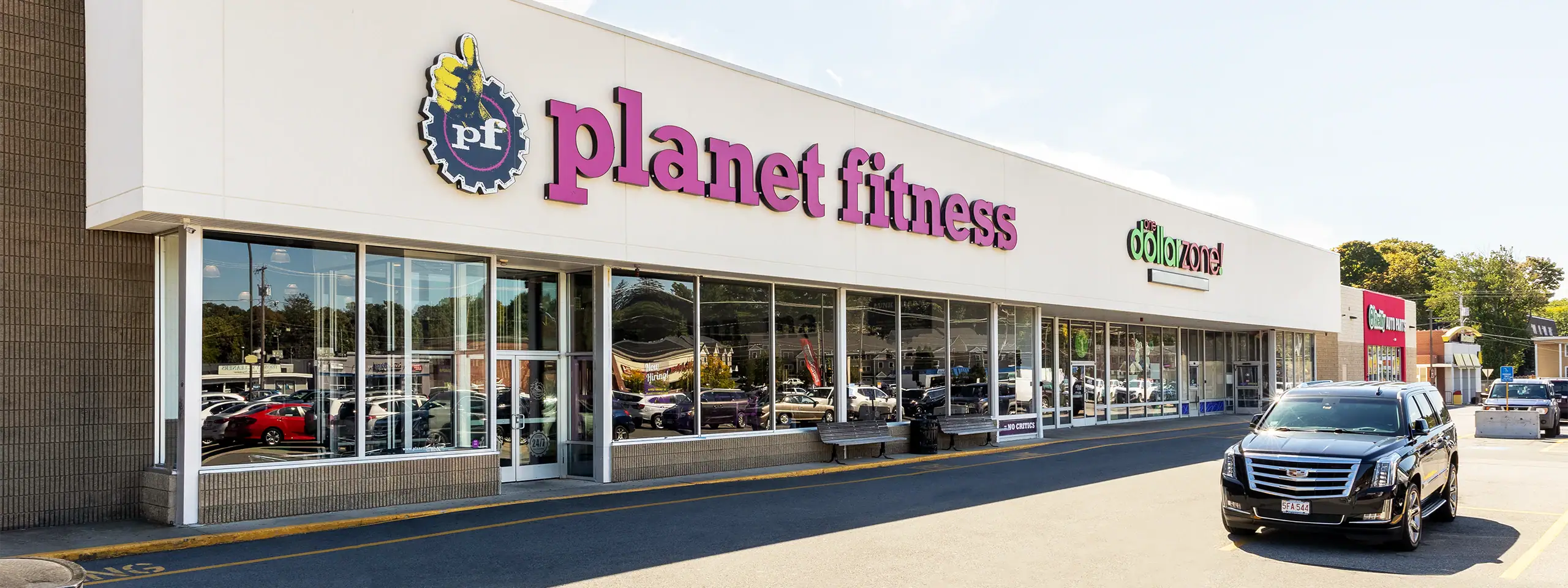 Planet Fitness gym storefront with large glass windows and parking lot.