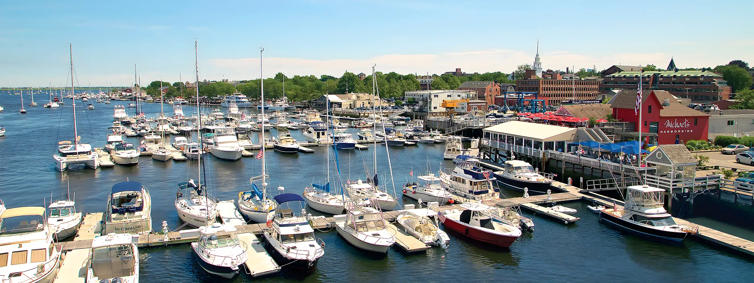 Marina with numerous sailboats and yachts docked in a harbor, New England.