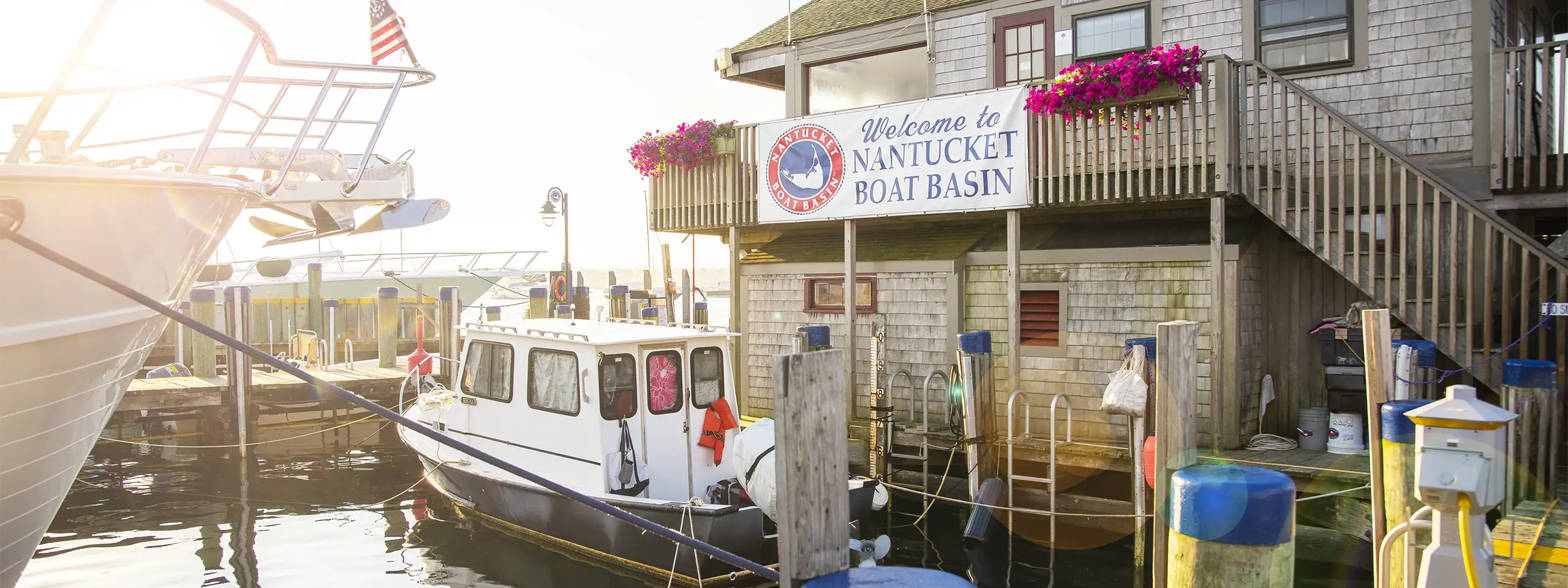 People boarding boats at Nantucket Boat Basin with a welcoming sign in the background.