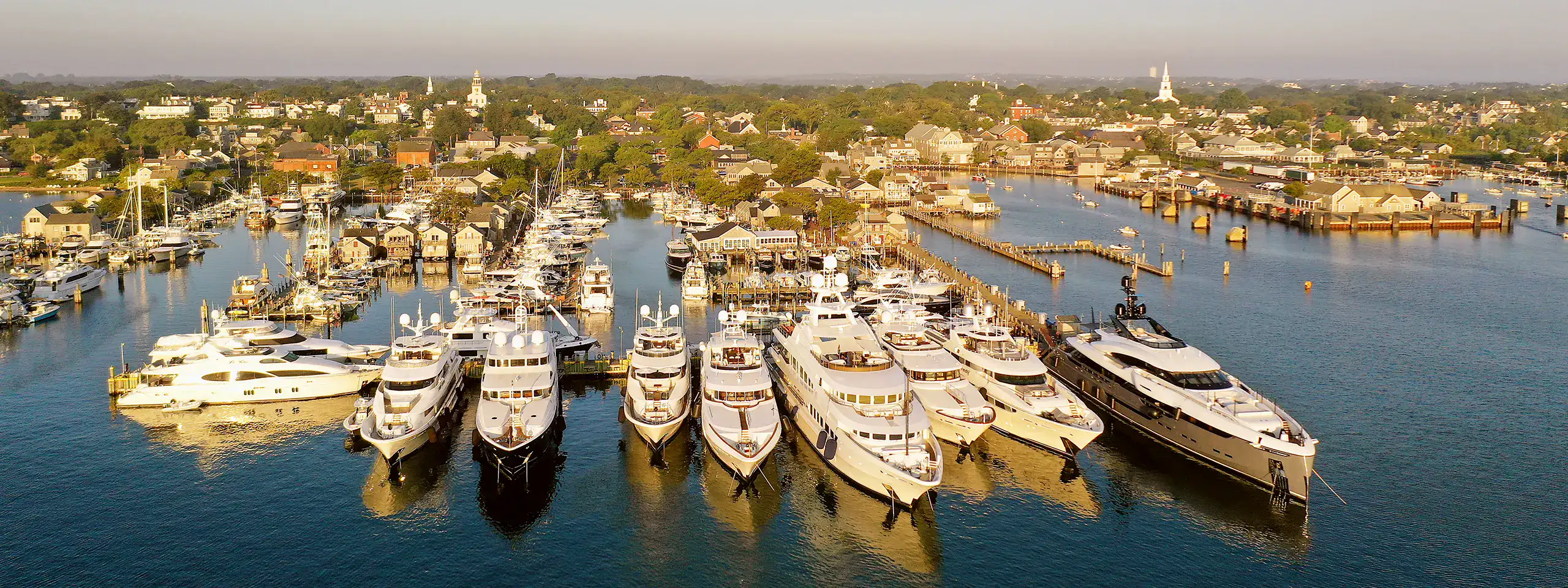 Aerial view of luxury yachts docked at a marina in New England.