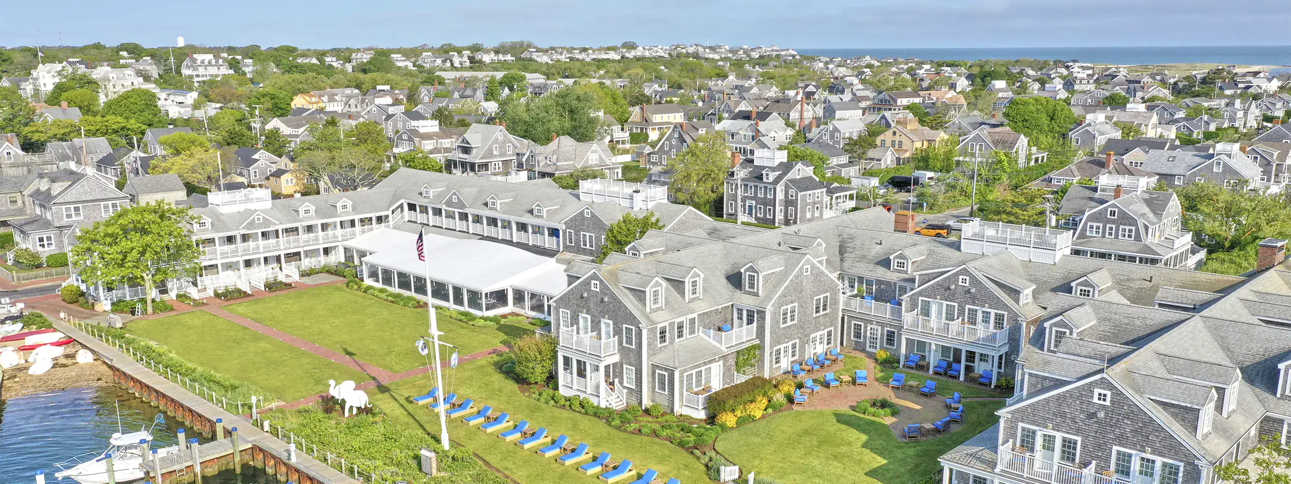 Aerial view of a residential neighborhood with a pond and green spaces in New England.