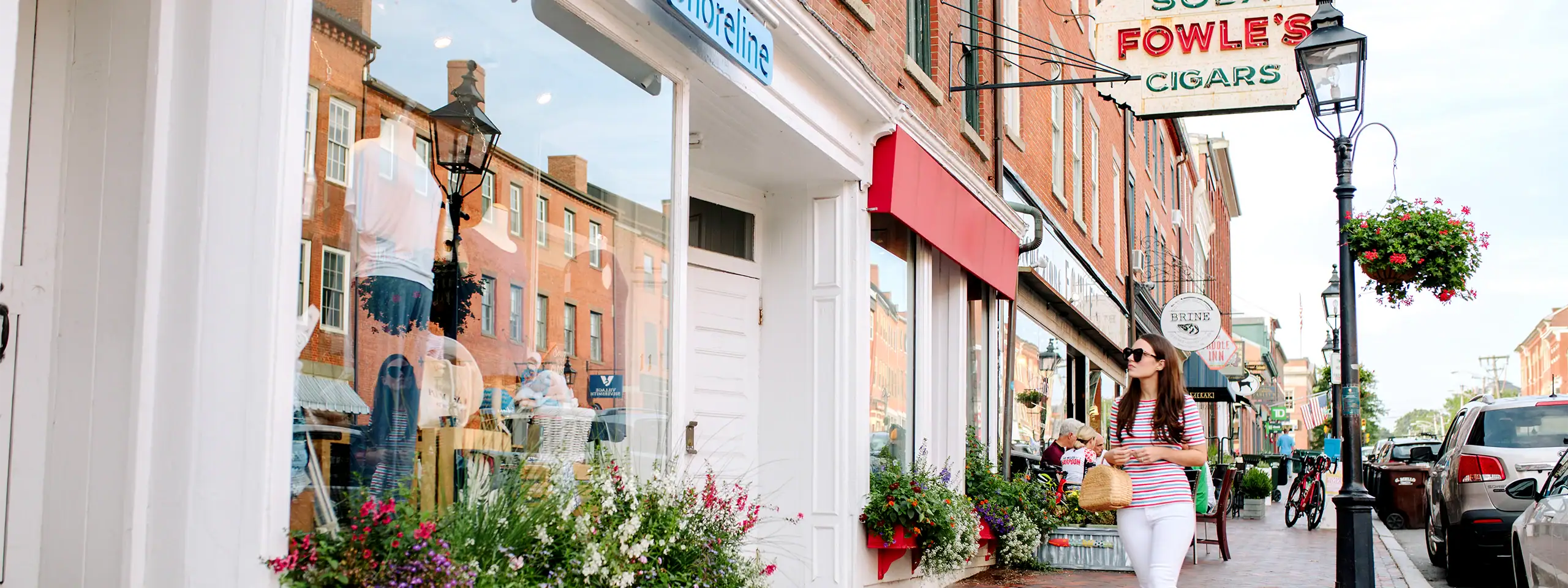Street view of a boutique with flower boxes and a cigar shop in a historic district.