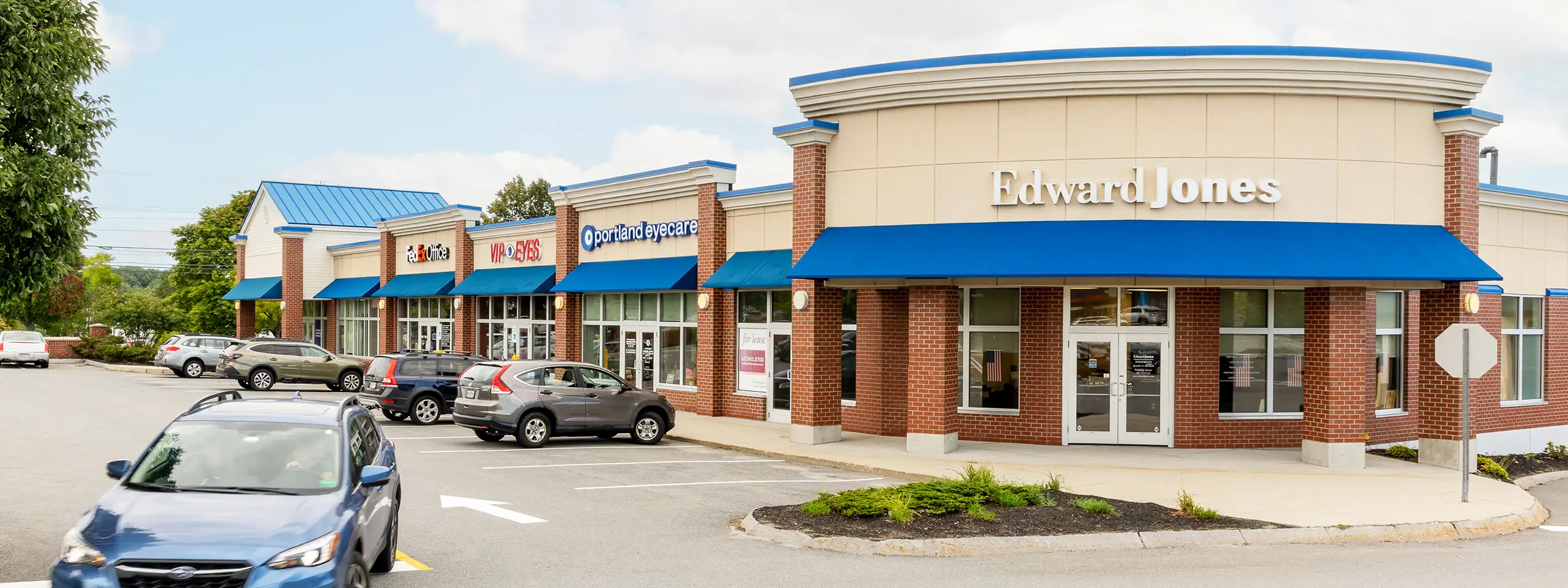 Edward Jones financial office in a shopping plaza with parked cars and blue awnings.
