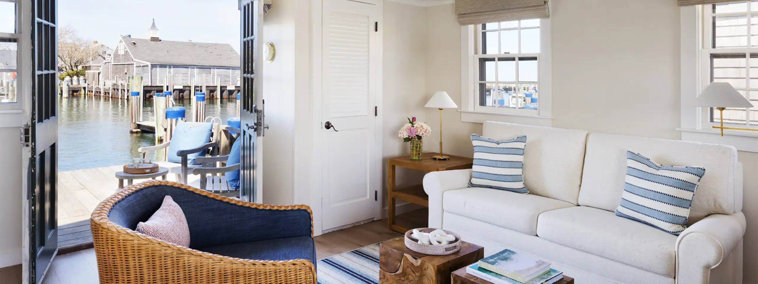Bright living room with white sofa, striped pillows, and view of waterfront dock.