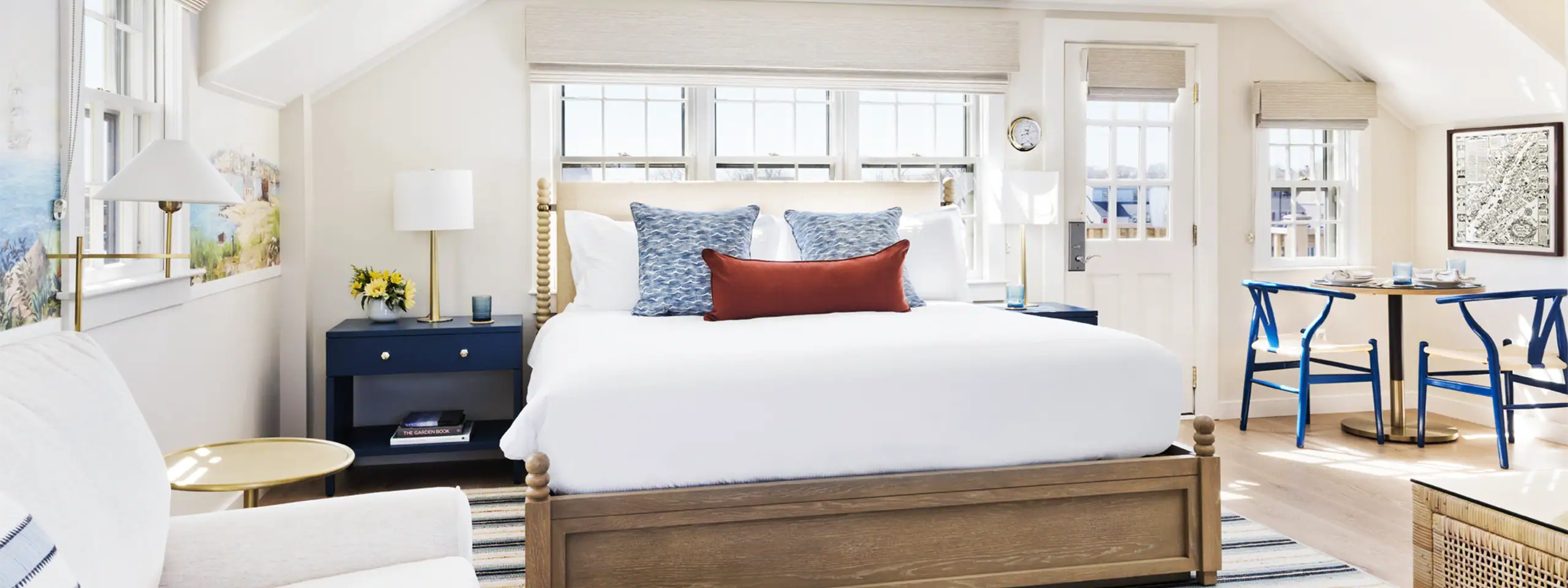 Bright bedroom with white walls, large bed, blue nightstand, and window views.