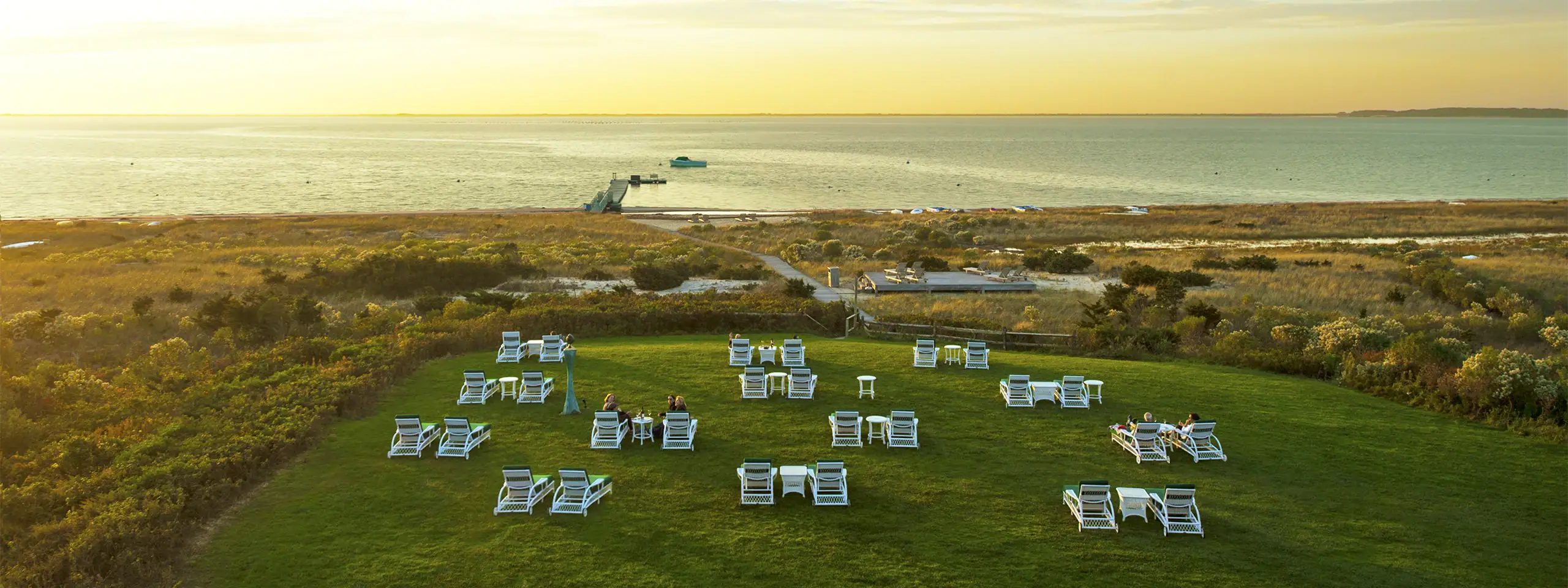 Beachfront with lounge chairs and ocean view at sunset.