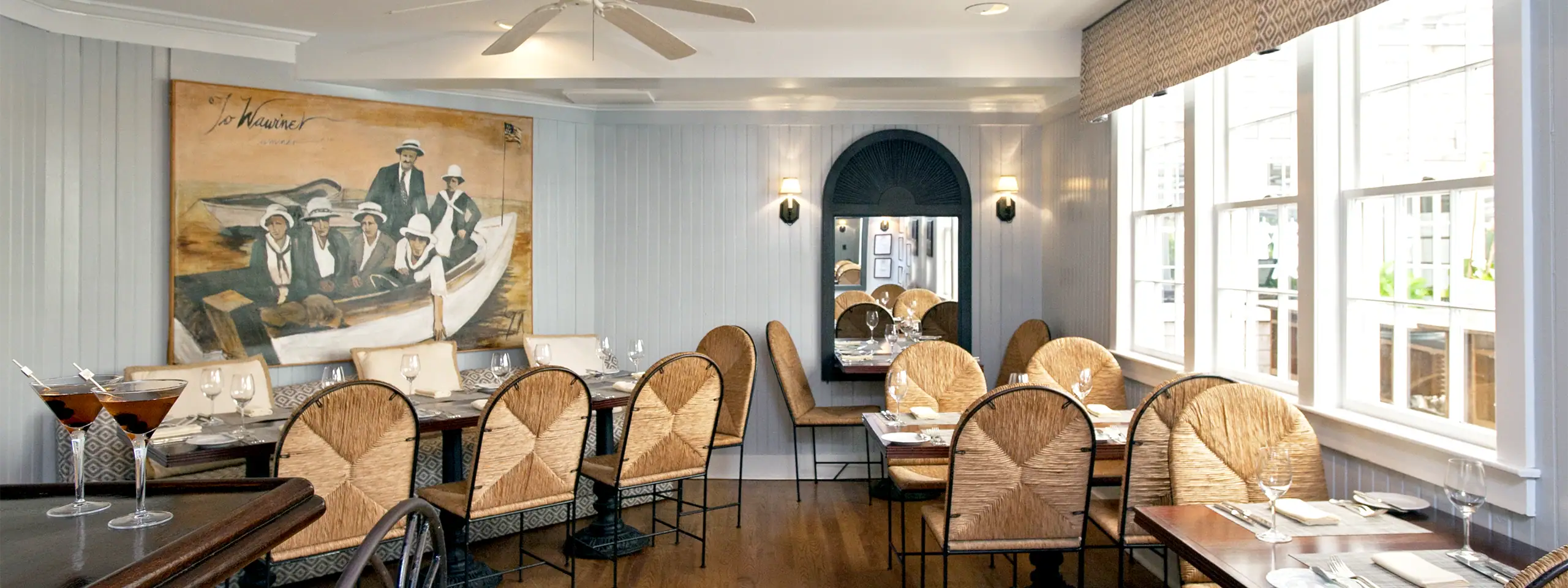 Elegant restaurant interior with large windows, round tables, and plush chairs.