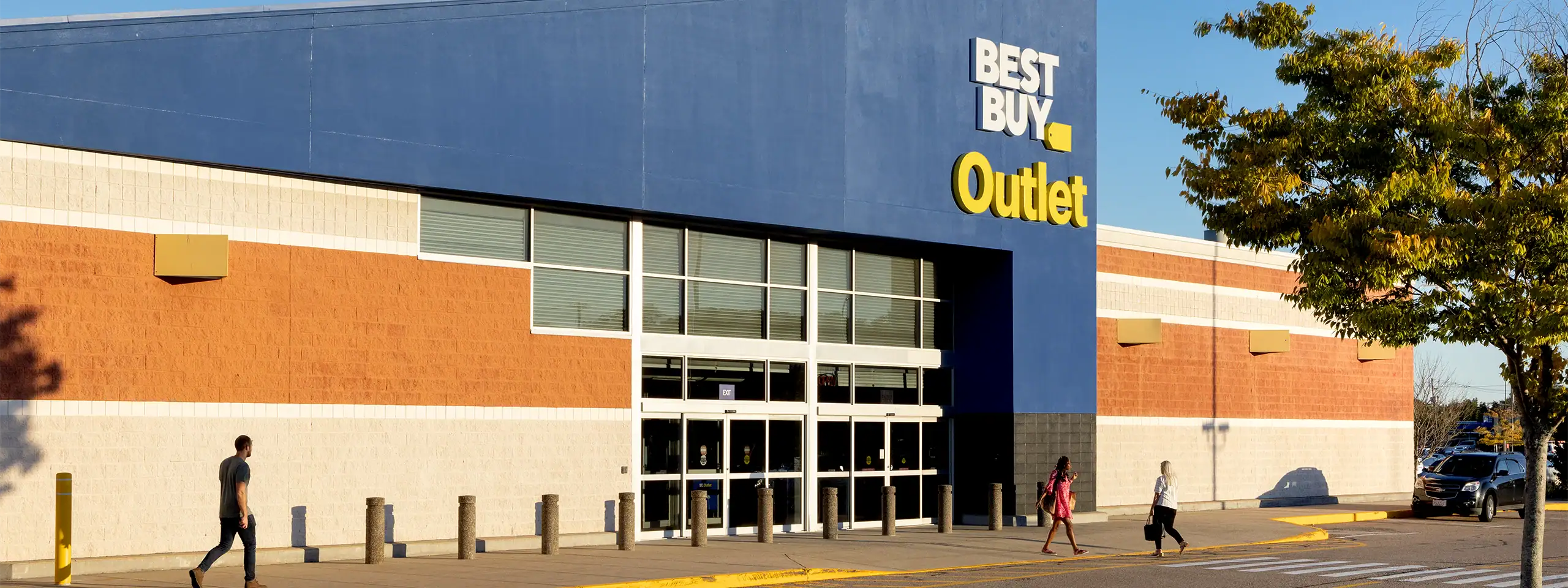 Exterior view of Best Buy Outlet store with blue facade and large glass entrance.