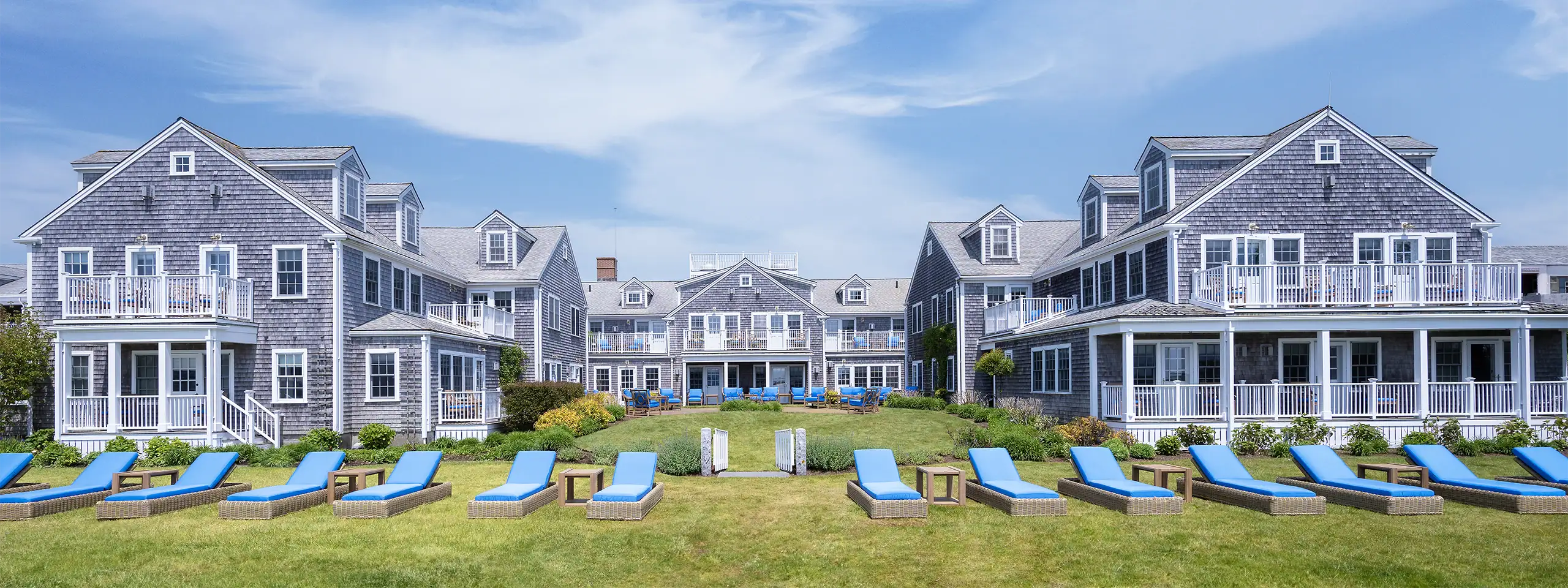 Luxury waterfront residential complex with outdoor lounge chairs and lush landscaping.