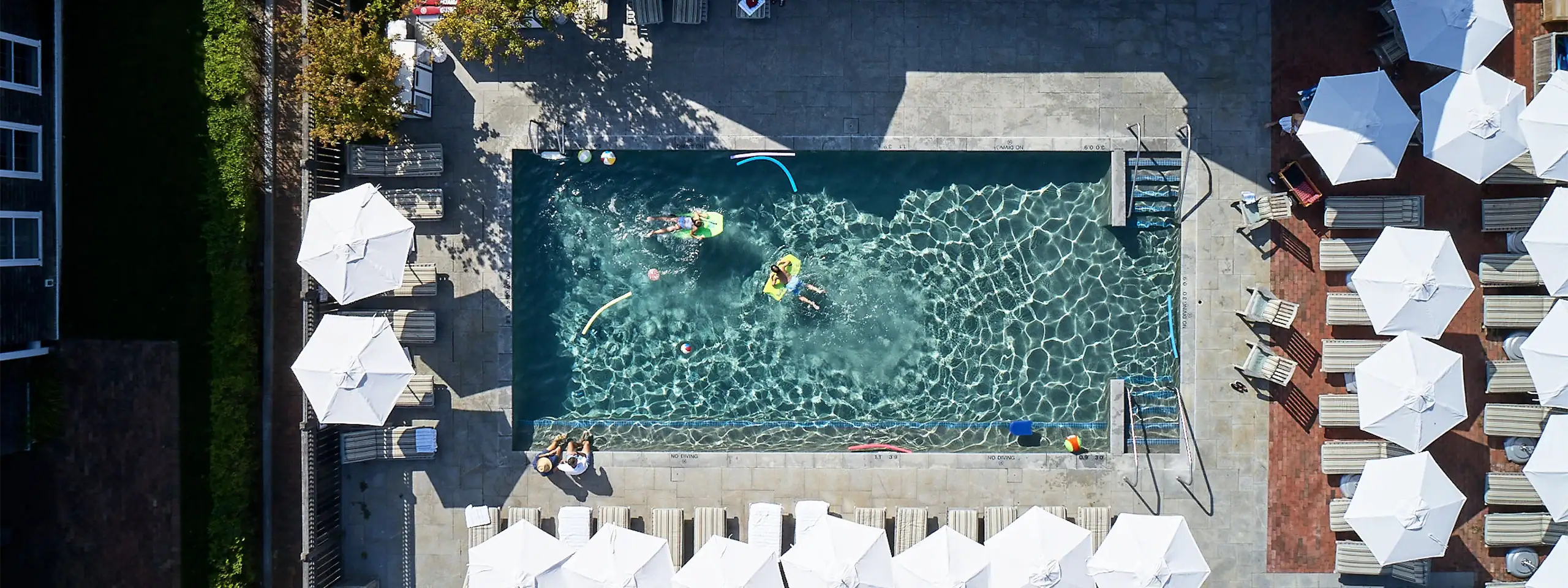 Aerial view of a swimming pool with umbrellas and lounge chairs around it.