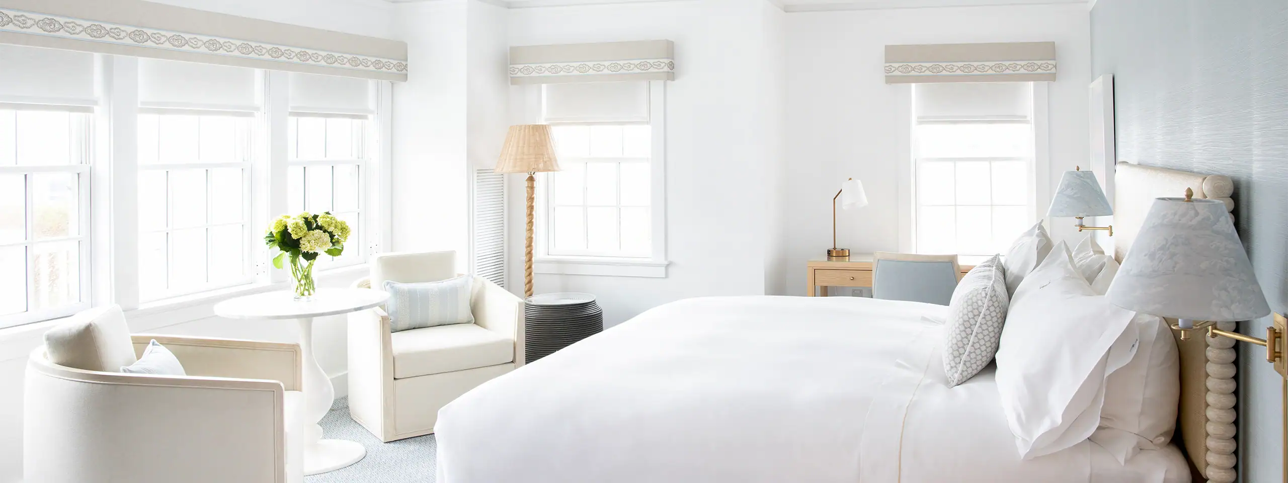 Bright, modern bedroom with white furniture and large windows.