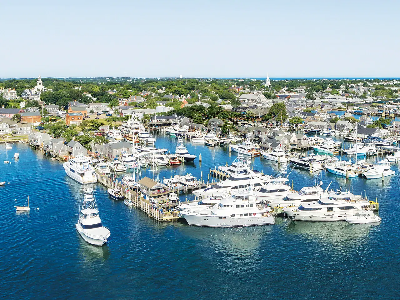 Aerial view of a marina with yachts and boats docked in a coastal town.