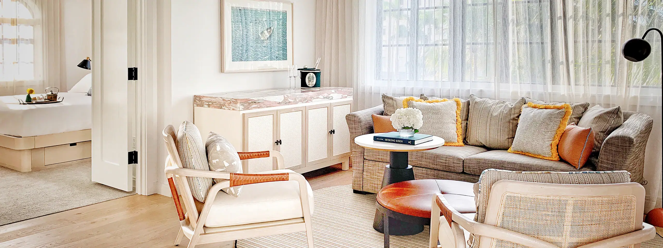 Bright living room with beige sofa, armchair, and large window with curtains.
