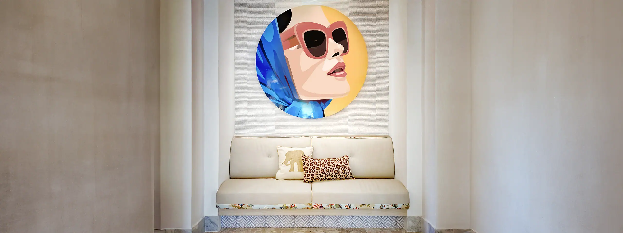 Decorative wall art of a woman's face with sunglasses above a white sofa in a modern room.