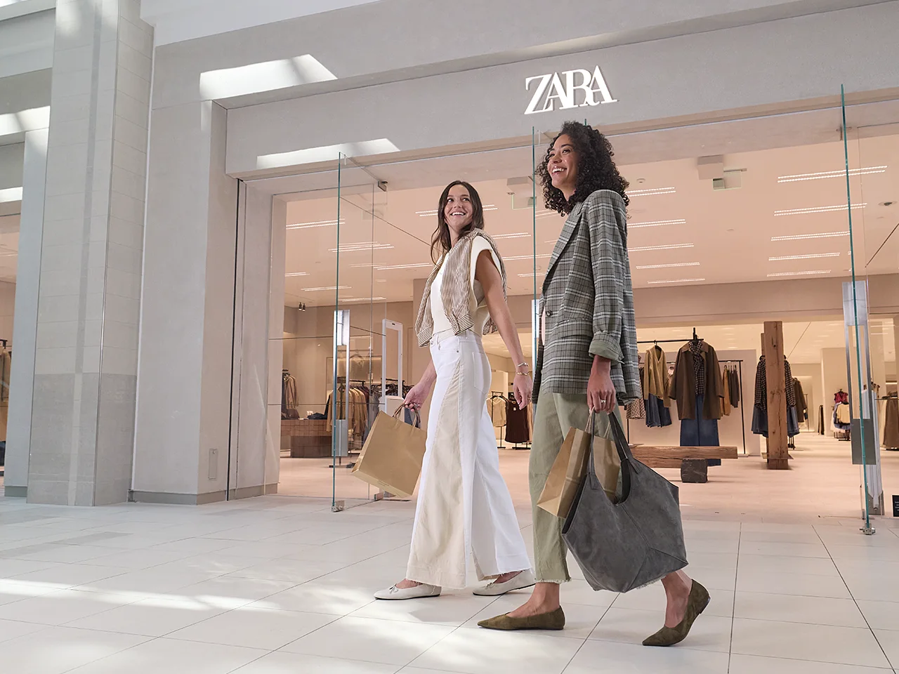 Shoppers walking in front of Zara storefront in CambridgeSide.