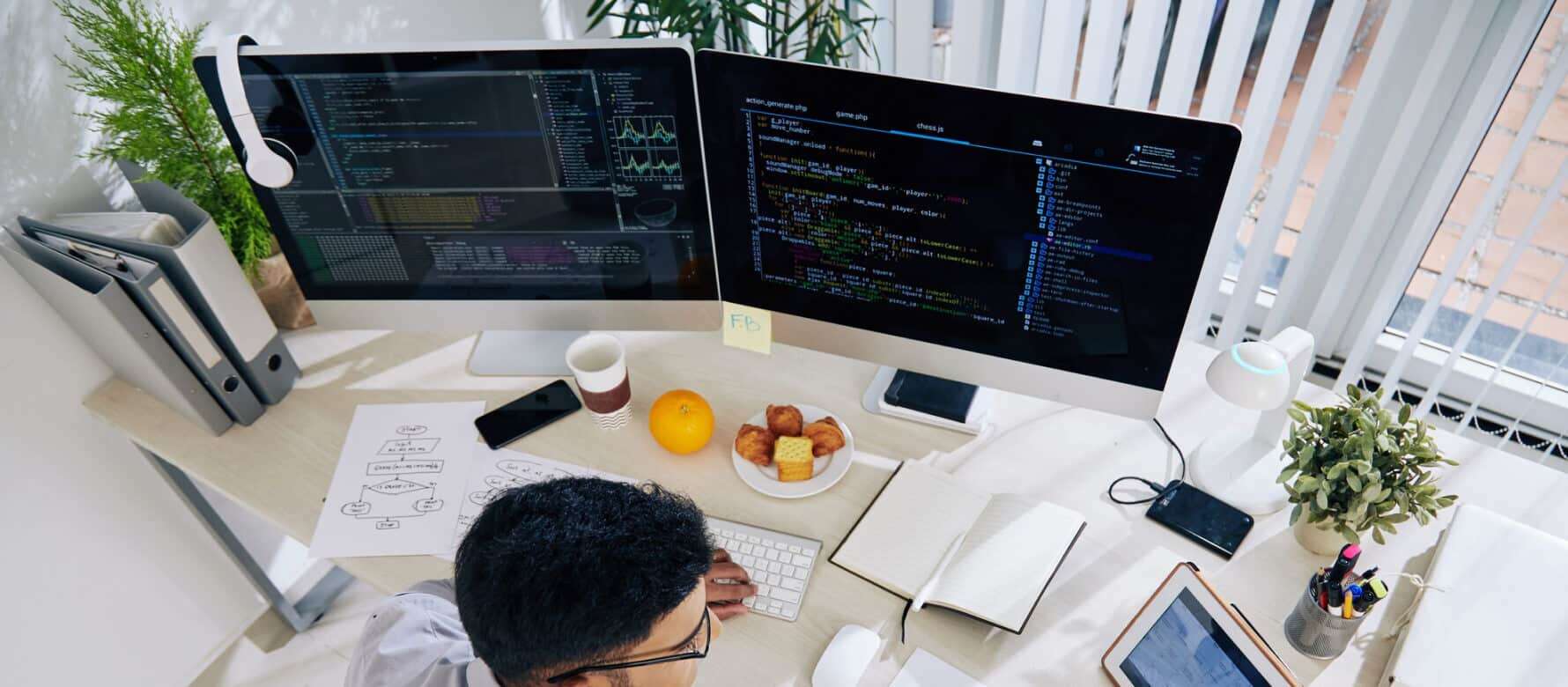Coding workspace with dual monitors and programming code, modern tech office setup.